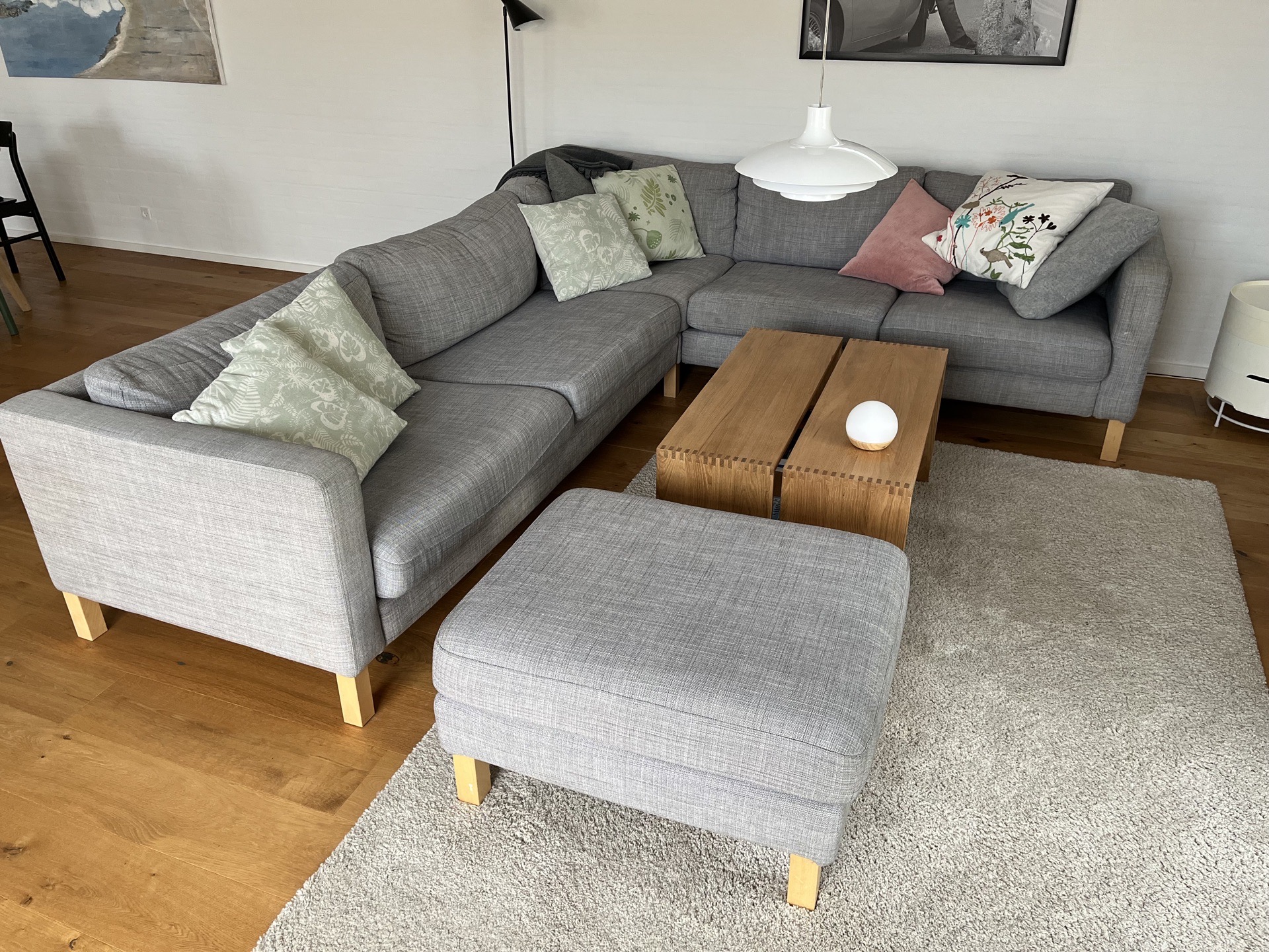 Hjørnesofa med puffe i lys grå stof og med ben i bøg. Pris 4.500,-